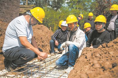 在湖南省常德市安乡县一建筑工地，技师（左一）向工人们讲解扎筋技巧。新华社记者 周勉摄